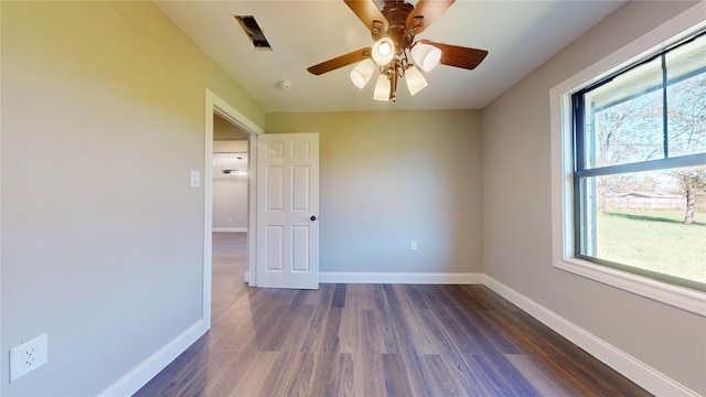 empty room with plenty of natural light, ceiling fan, and dark wood-type flooring