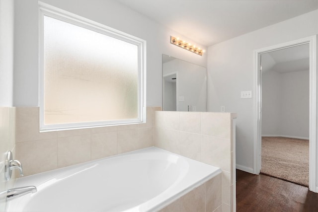 bathroom featuring tiled tub, hardwood / wood-style flooring, and plenty of natural light