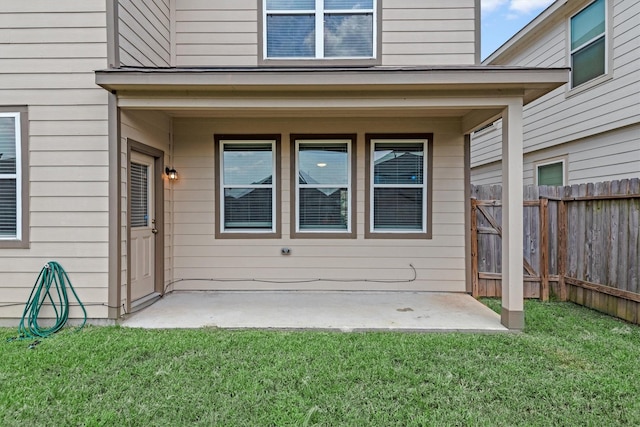 entrance to property with a patio area and a lawn