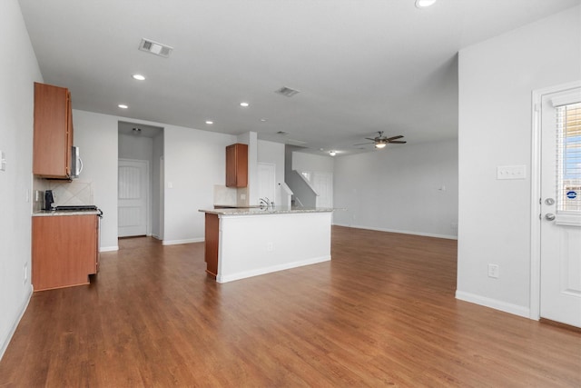 kitchen with tasteful backsplash, light stone countertops, hardwood / wood-style floors, and ceiling fan