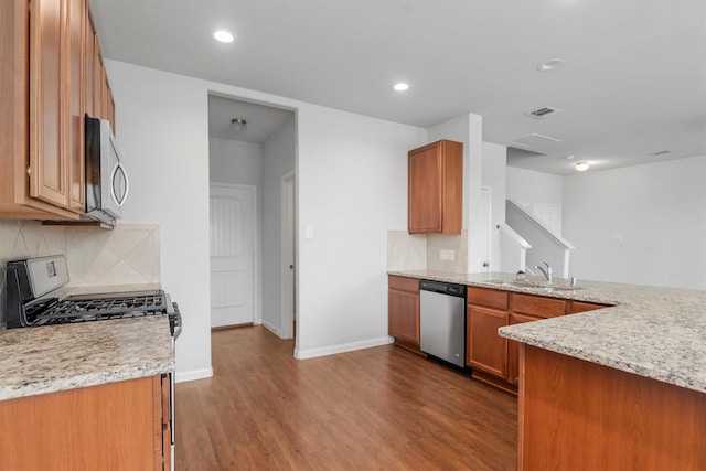 kitchen featuring wood-type flooring, sink, stainless steel dishwasher, and light stone counters