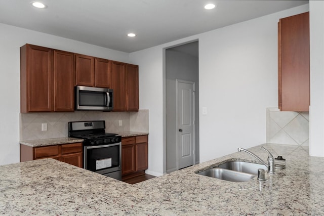 kitchen with light stone counters, sink, decorative backsplash, and stainless steel appliances