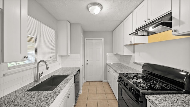 kitchen featuring black appliances, light stone countertops, white cabinetry, and sink