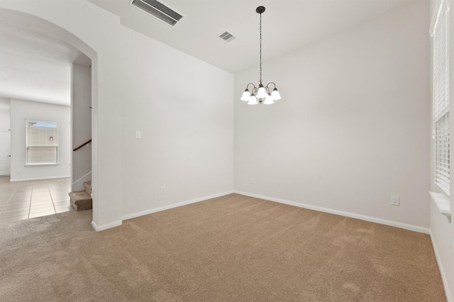 carpeted empty room with a notable chandelier