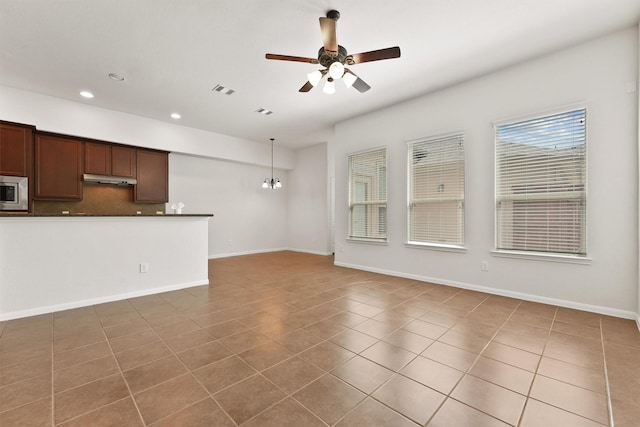 unfurnished living room featuring tile patterned floors and ceiling fan with notable chandelier