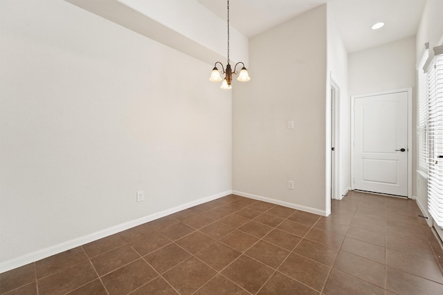 unfurnished room featuring dark tile patterned flooring and an inviting chandelier