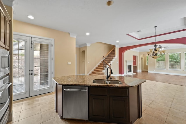 kitchen featuring a kitchen island with sink, ornamental molding, sink, dark brown cabinets, and decorative light fixtures