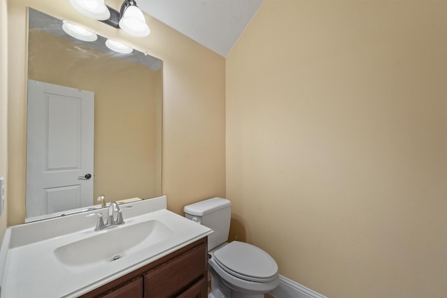 bathroom with toilet, vanity, and vaulted ceiling