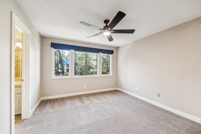 empty room with ceiling fan, light carpet, and a textured ceiling