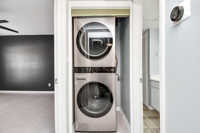 washroom featuring ceiling fan, stacked washer and dryer, and light tile patterned floors