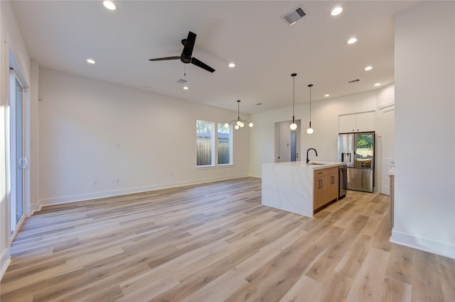 kitchen with stainless steel refrigerator with ice dispenser, sink, an island with sink, pendant lighting, and light hardwood / wood-style floors