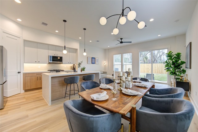 dining space with ceiling fan, sink, and light hardwood / wood-style flooring