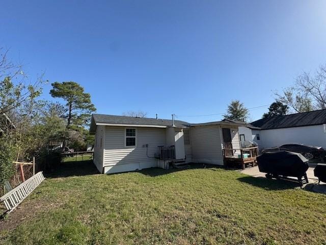 rear view of property with central AC unit and a yard