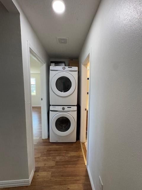 washroom with dark wood-type flooring and stacked washer / drying machine