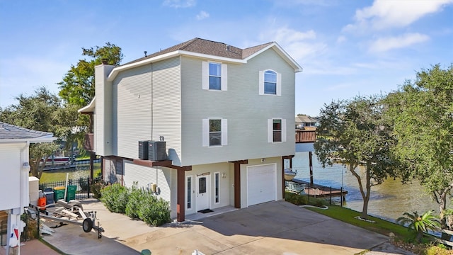 exterior space with a water view, a garage, and cooling unit