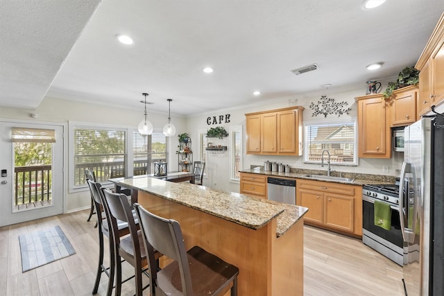 kitchen featuring light stone countertops, sink, hanging light fixtures, a kitchen island, and appliances with stainless steel finishes