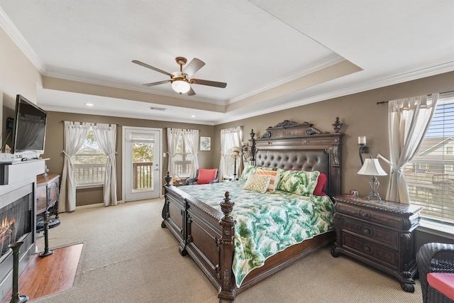 carpeted bedroom featuring ceiling fan, a raised ceiling, crown molding, and access to outside