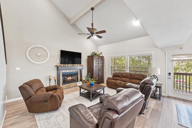 living room with beamed ceiling, ceiling fan, light wood-type flooring, and high vaulted ceiling