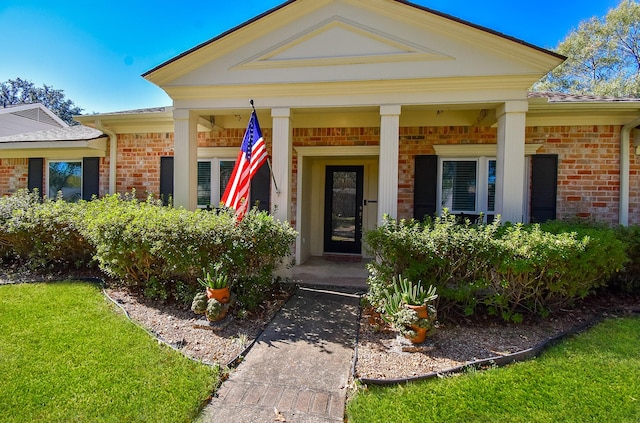 property entrance with covered porch and brick siding