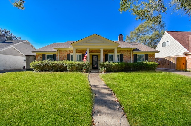 view of front of house featuring brick siding, fence, roof with shingles, a front lawn, and a chimney