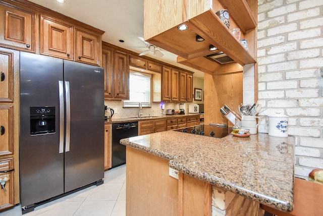 kitchen featuring light tile patterned floors, tasteful backsplash, brown cabinetry, black appliances, and a sink