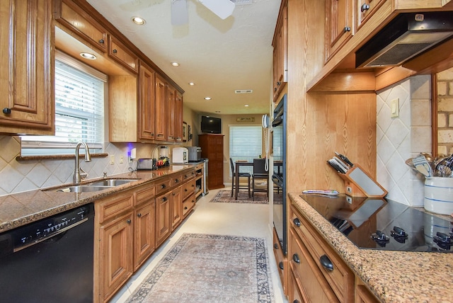 kitchen with tasteful backsplash, recessed lighting, brown cabinetry, a sink, and black appliances