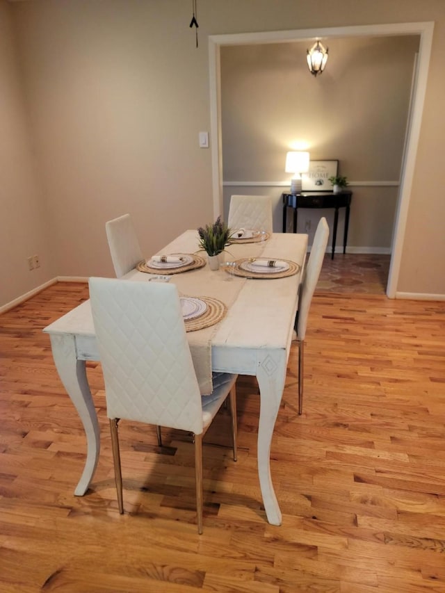 dining space featuring light wood-style flooring and baseboards