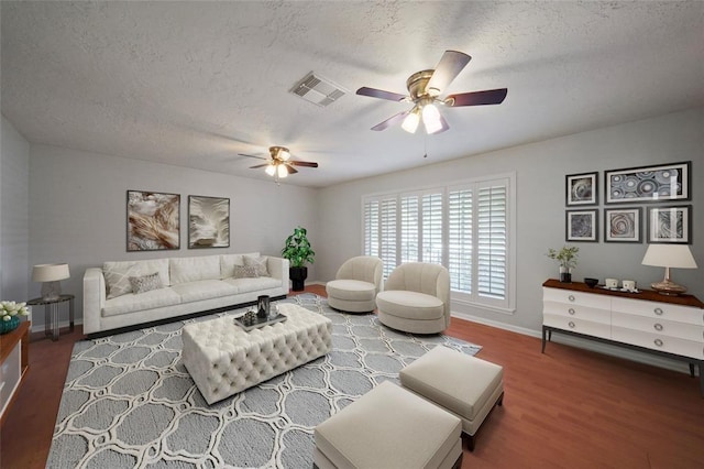 living room featuring hardwood / wood-style floors, ceiling fan, and a textured ceiling