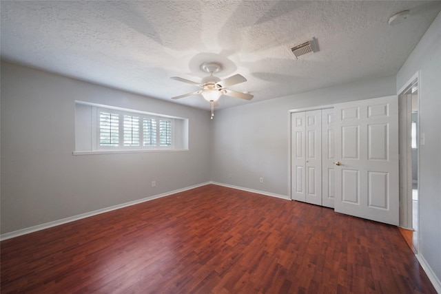 unfurnished bedroom with a textured ceiling, ceiling fan, a closet, and dark hardwood / wood-style floors