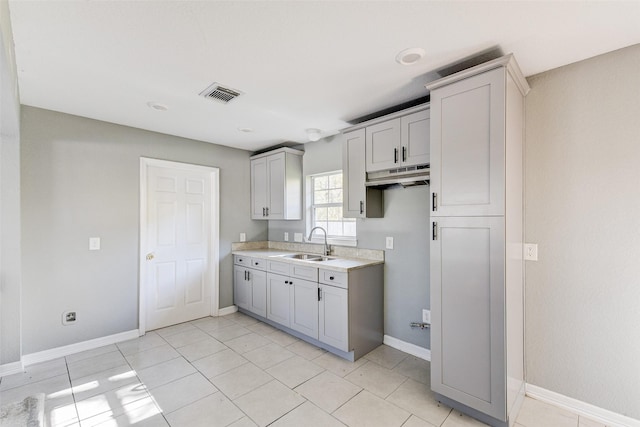 kitchen featuring gray cabinets, sink, and light tile patterned flooring