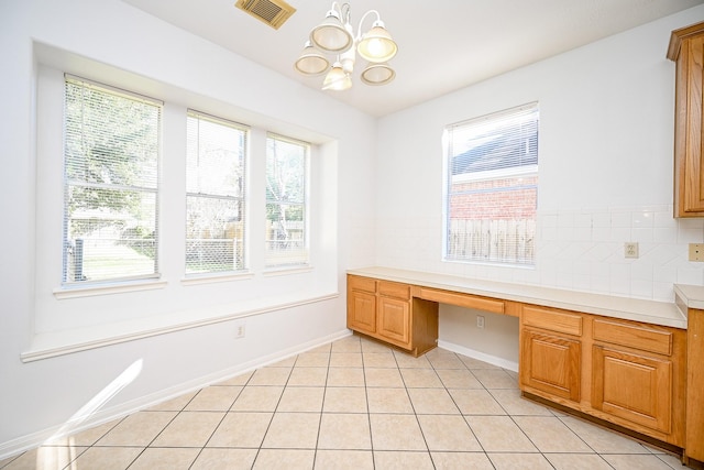 unfurnished office featuring light tile patterned flooring, built in desk, and an inviting chandelier