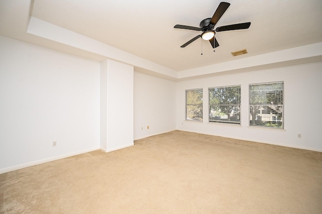 unfurnished room with a tray ceiling, ceiling fan, and light colored carpet