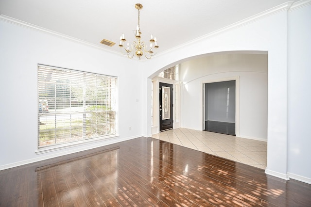 spare room with crown molding, hardwood / wood-style floors, and a chandelier