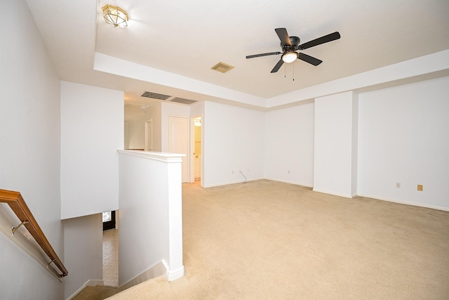 carpeted empty room with a tray ceiling and ceiling fan