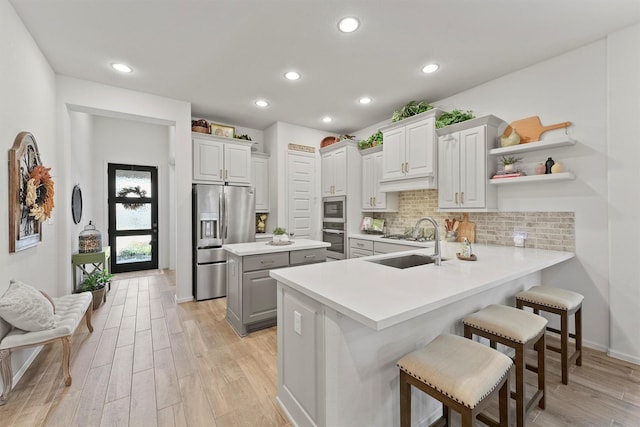 kitchen featuring kitchen peninsula, appliances with stainless steel finishes, tasteful backsplash, a breakfast bar, and sink