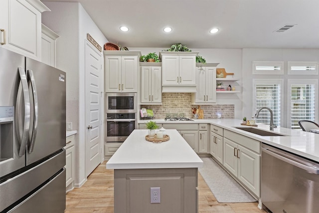 kitchen featuring sink, kitchen peninsula, decorative backsplash, white cabinets, and appliances with stainless steel finishes