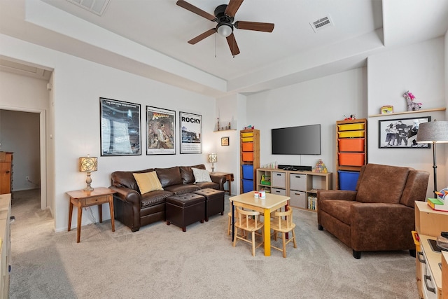 carpeted living room with a tray ceiling and ceiling fan