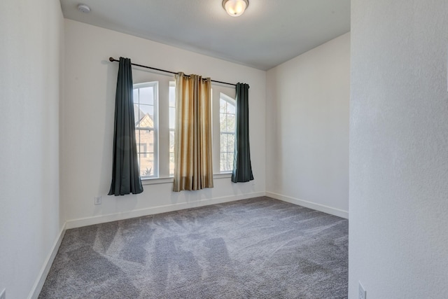 carpeted spare room featuring baseboards