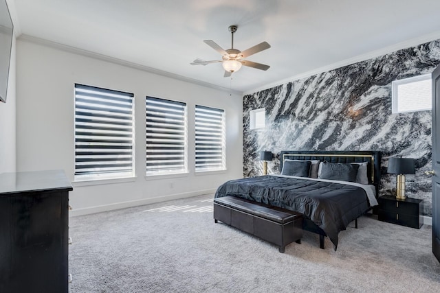 carpeted bedroom featuring ornamental molding, a ceiling fan, an accent wall, and baseboards