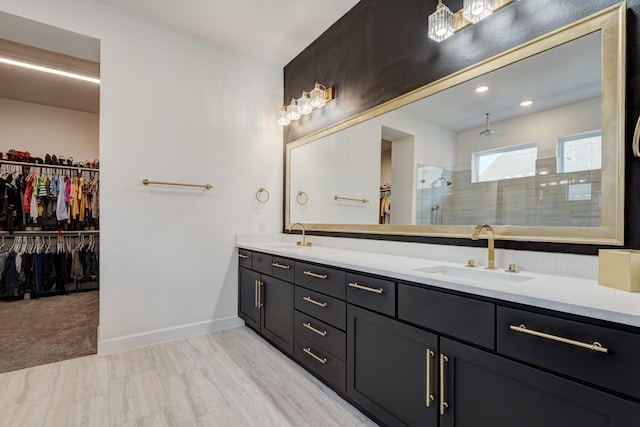 bathroom with a walk in closet, a walk in shower, double vanity, and a sink