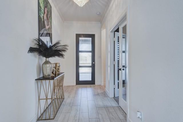 doorway featuring baseboards, an inviting chandelier, and crown molding