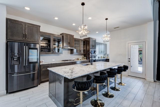 kitchen featuring light stone countertops, sink, a kitchen breakfast bar, an island with sink, and appliances with stainless steel finishes