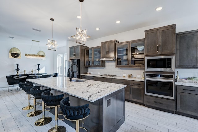 kitchen with tasteful backsplash, a breakfast bar, stainless steel appliances, dark brown cabinets, and a sink