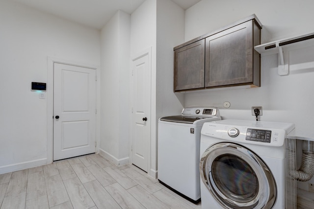 laundry room featuring washer and clothes dryer, cabinets, and light wood-type flooring