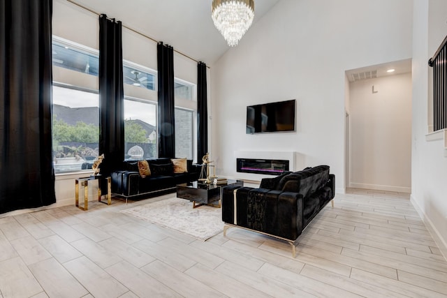 living area featuring visible vents, a chandelier, baseboards, wood finished floors, and high vaulted ceiling