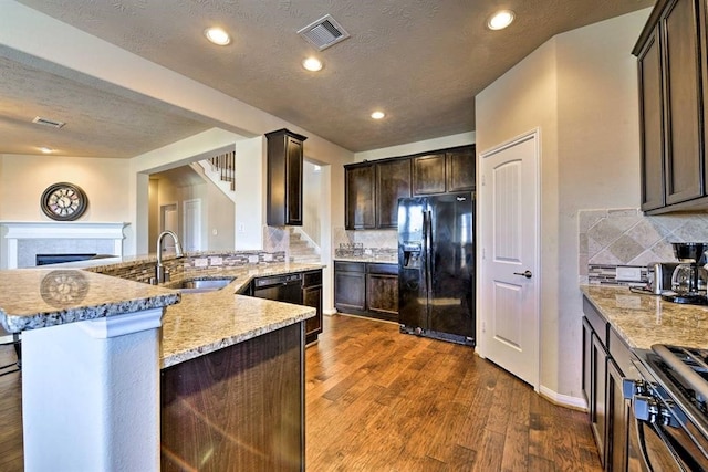 kitchen featuring a kitchen bar, black appliances, sink, decorative backsplash, and dark hardwood / wood-style flooring