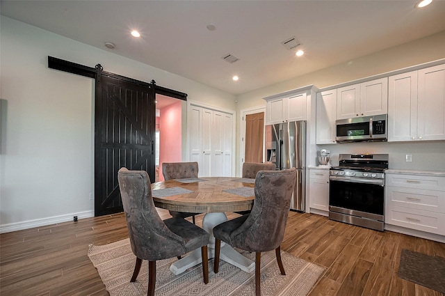 dining area featuring wood-type flooring and a barn door