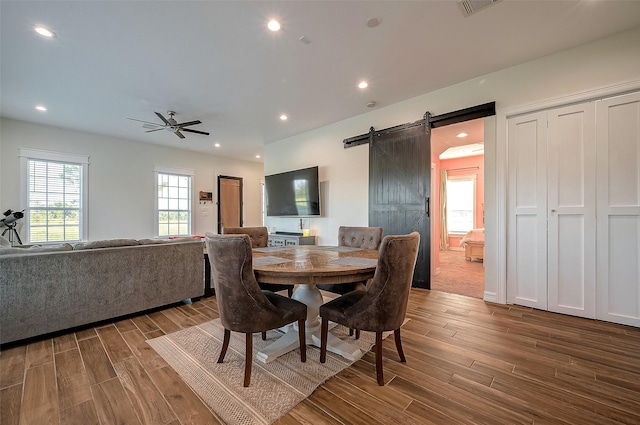 dining area featuring ceiling fan and a barn door