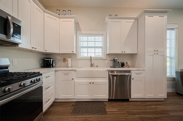 kitchen with white cabinetry, sink, dark wood-type flooring, stainless steel appliances, and backsplash