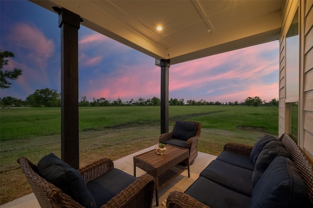 patio terrace at dusk featuring outdoor lounge area, a rural view, and a yard